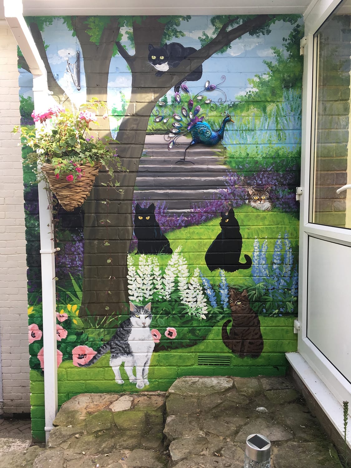 Hand painted garden mural of cats around a tree